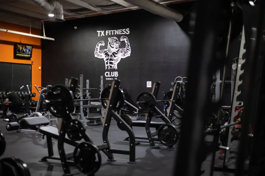 Spacious gym floor at TX Fitness with free weights and tiger mural in Forney TX